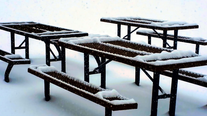 Snow-covered picnic tables in winter park