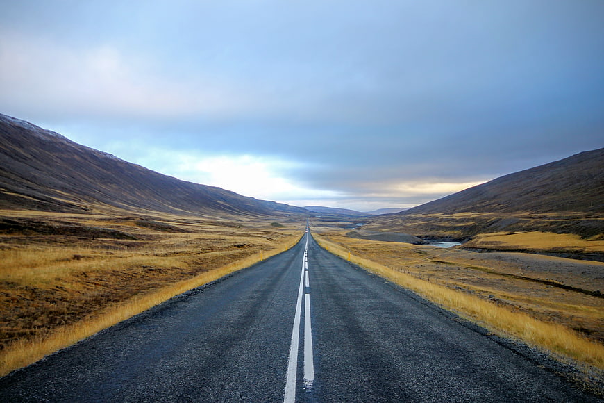 Empty asphalt road stretching through vast autumn landscape