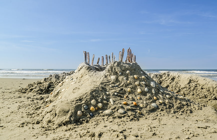 Sandcastle with shells and sticks on sunny beach