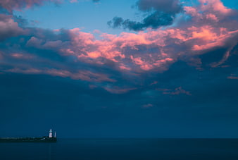 Dramatic Pink Clouds Over Dark Sea With Distant Lighthouse