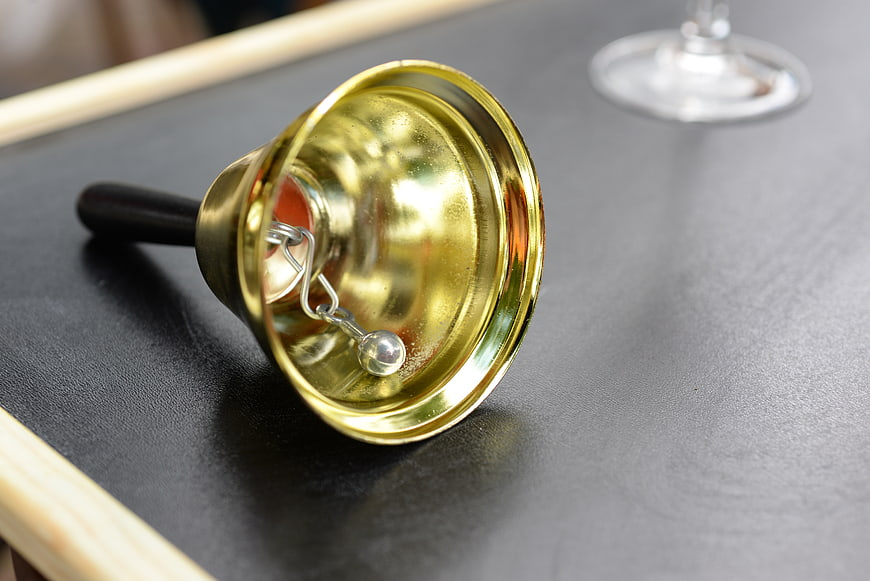 Close-up of a brass hand bell on a dark table