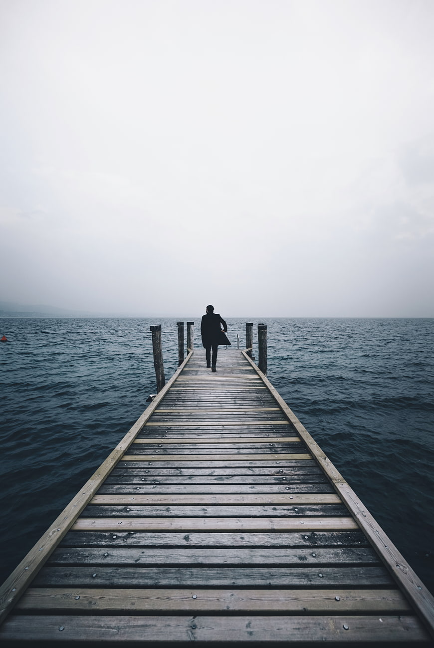 Man in Suit Walking on Wooden Pier into Foggy Sea
