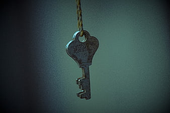 Antique metal key hanging from a rope against a dark background