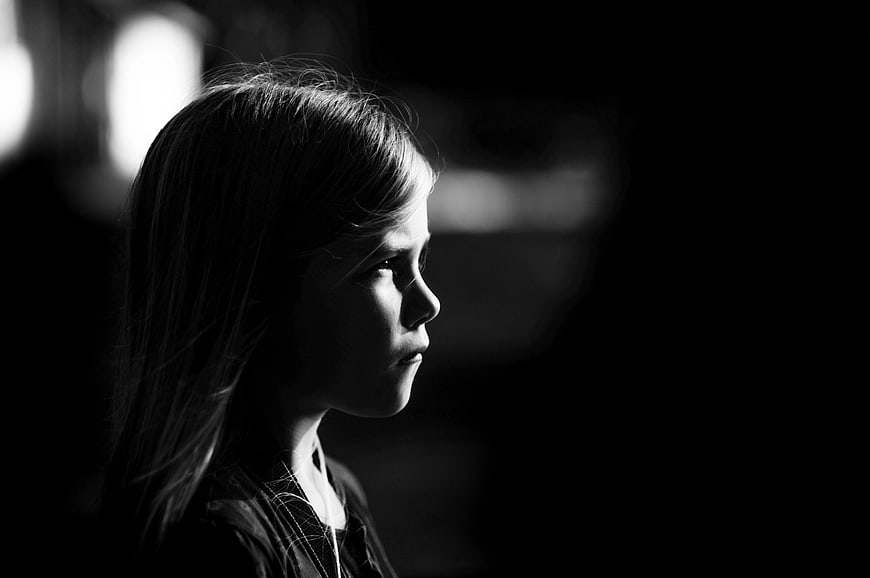Black and white profile portrait of a young girl in shadow