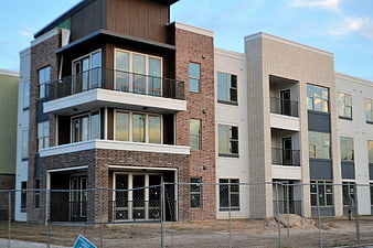 Modern brick apartment complex under construction with chain link fence