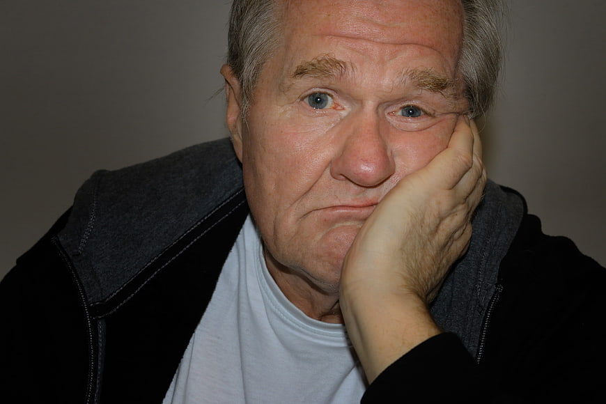 Portrait of bored senior man resting chin on hand