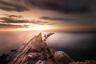 Dramatic Sunset Over Rocky Coastal Peninsula and Ocean