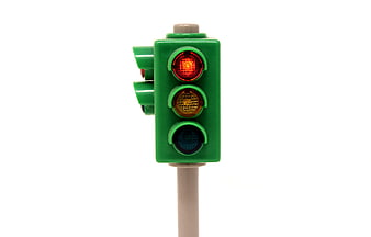 Green toy traffic light with red signal illuminated on white background