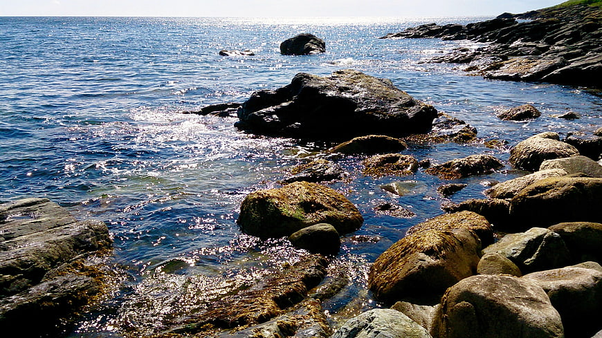 Sunny Rocky Coastline with Sparkling Blue Ocean Water