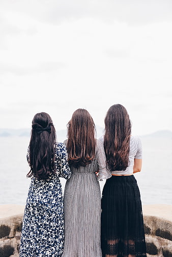 Three Women Standing Back to Back by the Sea
