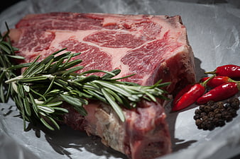 Raw T-Bone Steak with Rosemary and Chili Peppers