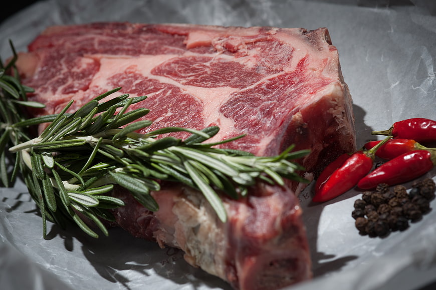 Raw T-Bone Steak with Rosemary and Chili Peppers
