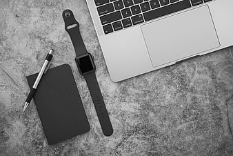 Minimalist black and white workspace with laptop, notebook, and smartwatch