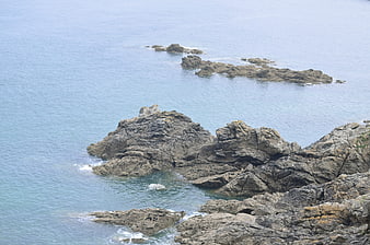 Rugged coastal rocks in calm blue ocean water