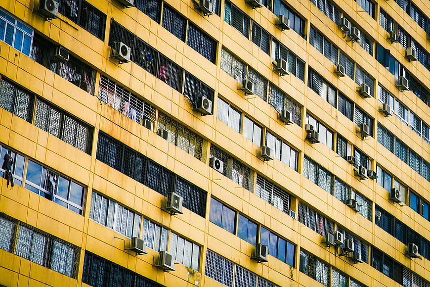 Yellow Residential Building Facade with Windows and Air Conditioners