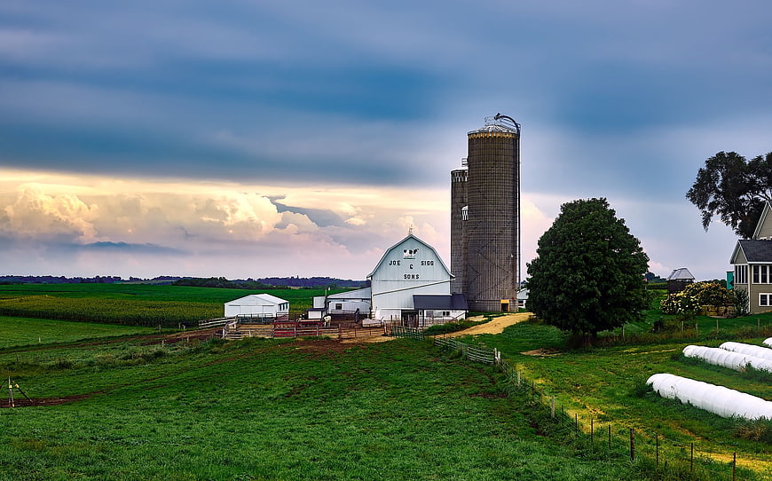 Rural Farm Landscape with Silos and Barn Under Dramatic Sky