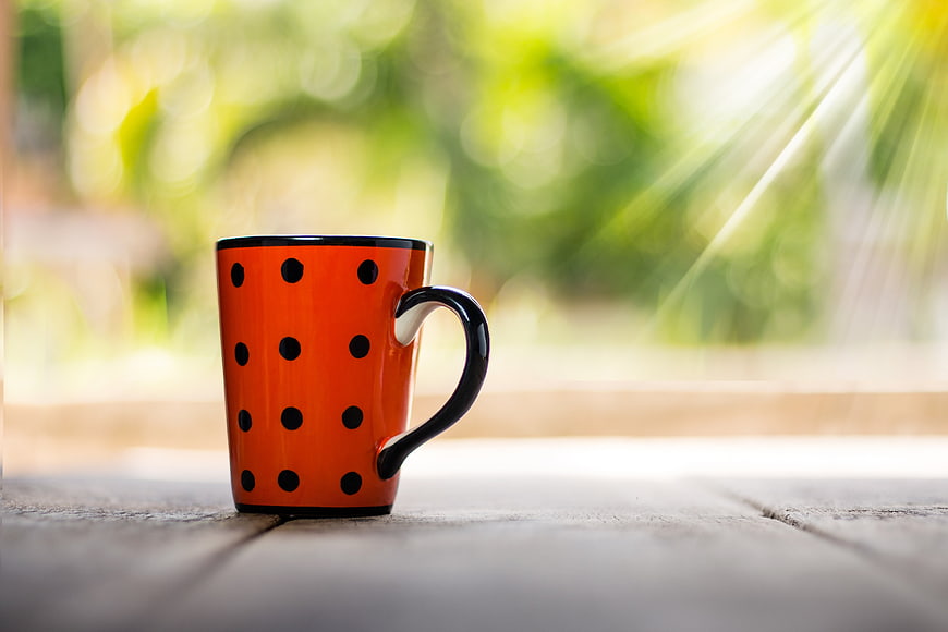 Orange Polka Dot Mug on Wooden Table with Sunlight