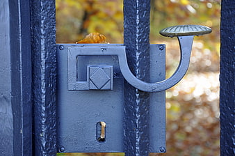 Close-up of vintage blue metal gate latch with autumn leaf