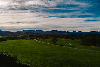Serene Green Landscape with Church and Distant Mountains