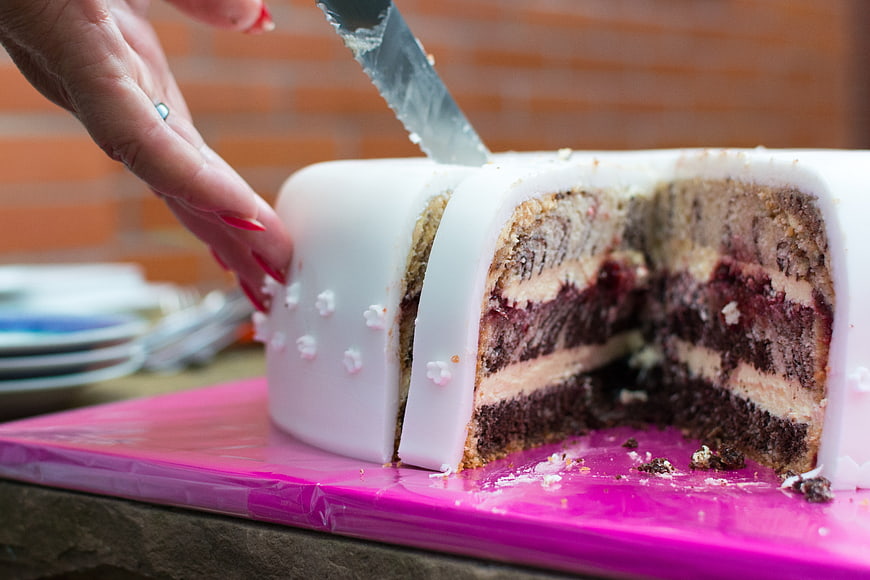 Close-up of hand slicing layered birthday cake