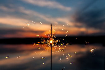 Sparkler Burning Against Sunset Sky Over Water