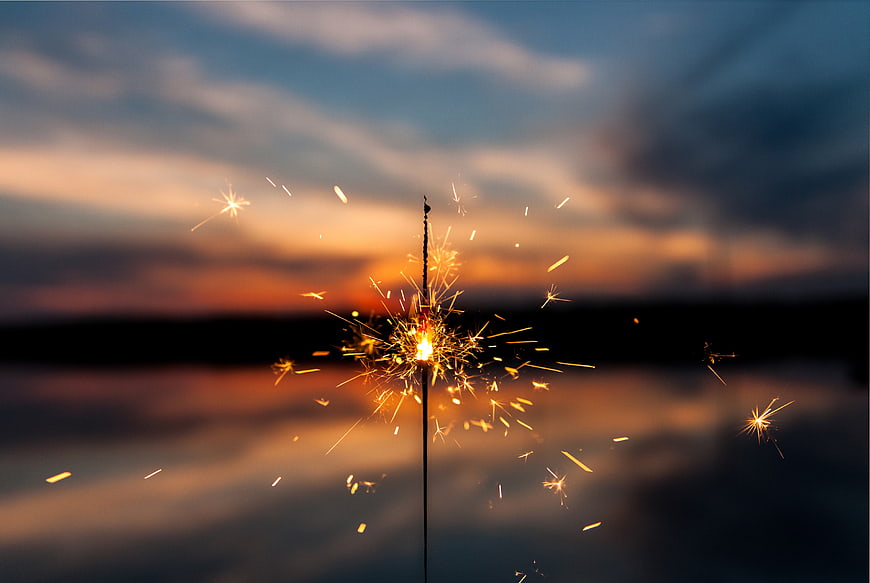 Sparkler Burning Against Sunset Sky Over Water