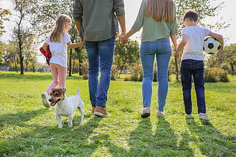 Happy family walking with dog in sunny park