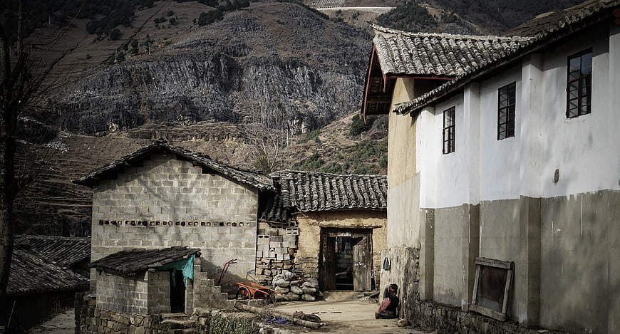 Rural village houses near mountain cliff with woman sitting
