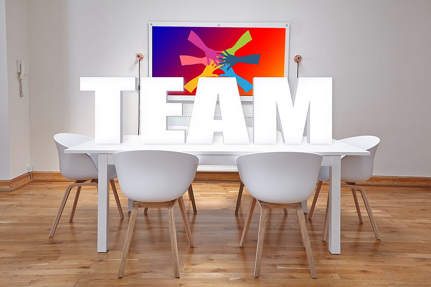 White TEAM letters on modern office table with colorful background