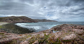 Dramatic Rocky Coastline with Pebble Beach and Overcast Sky
