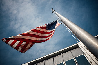 Low angle view of American flag waving against blue sky