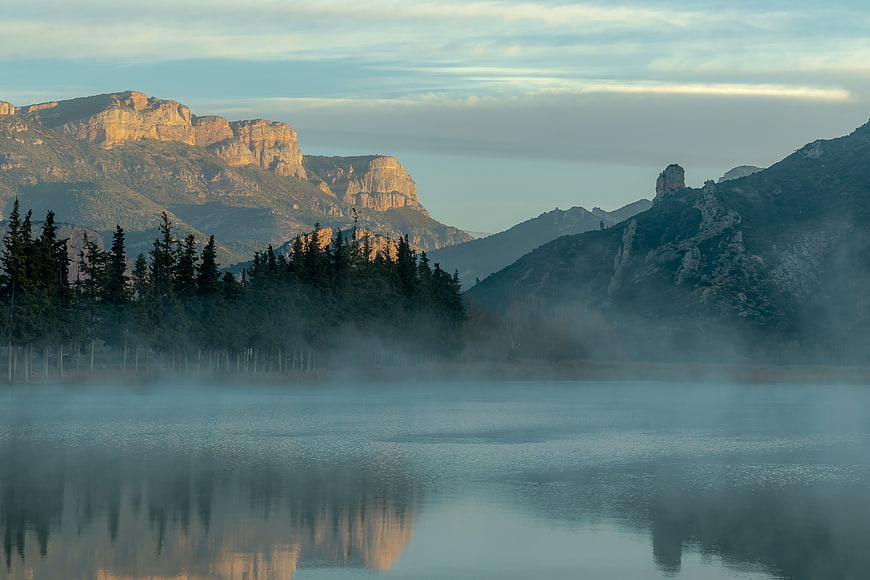 Misty morning landscape with mountains and lake reflection