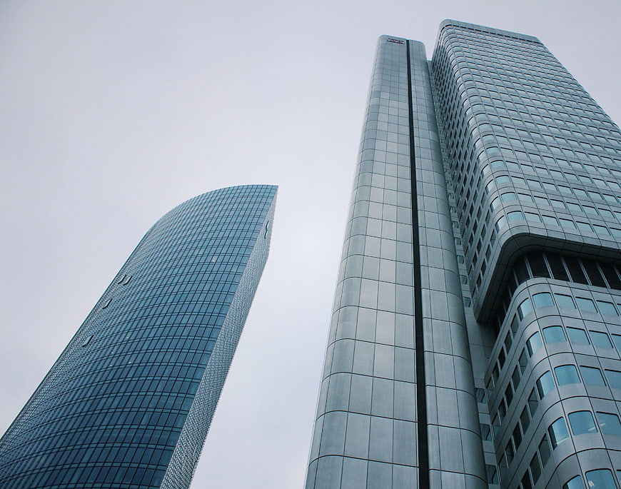 Low-angle view of modern glass skyscrapers against gray sky