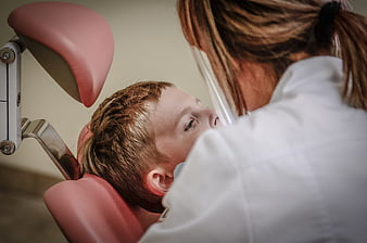 Dentist examining young boy patient in dental chair