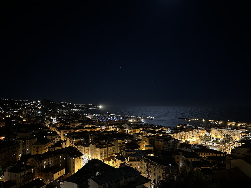 Nighttime panoramic view of coastal city skyline with harbor lights