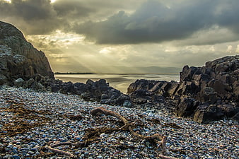 Dramatic Rocky Beach with Sunbeams Through Clouds