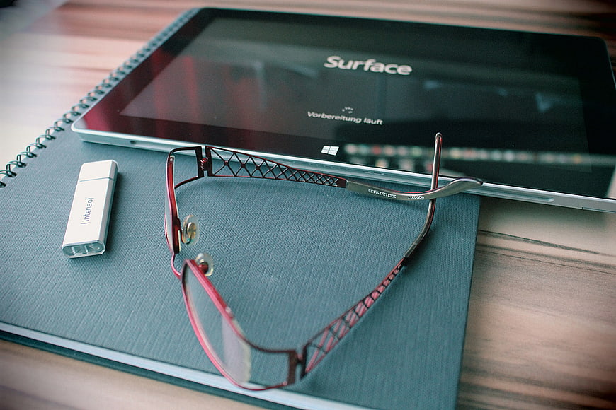 Modern workspace with tablet, glasses, and notebook