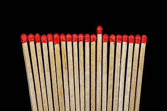 One Matchstick Standing Out Among Many on Black Background