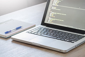 Laptop with CSS Code on Desk with Notebook