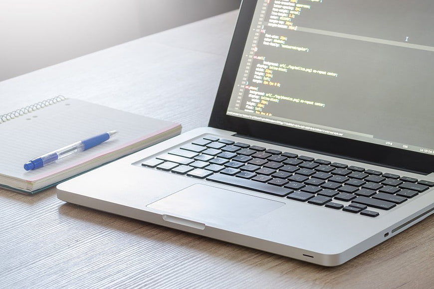 Laptop with CSS Code on Desk with Notebook