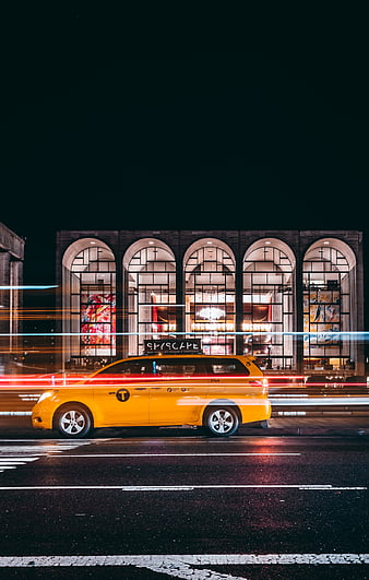 Yellow NYC Taxi Driving Past Museum at Night with Light Trails