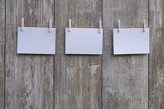 Blank lined paper sheets hanging on clothesline against rustic wood