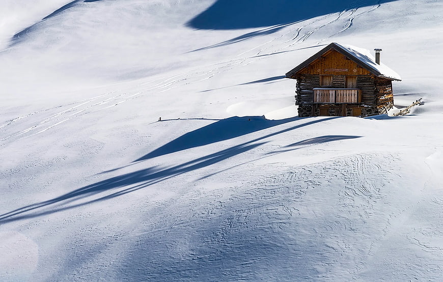 Solitary wooden cabin on snowy mountain slope