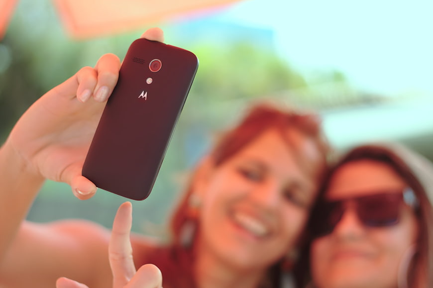 Close-up of hand holding smartphone taking selfie with friends