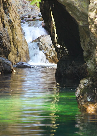 Hidden waterfall cascading into a serene green pool