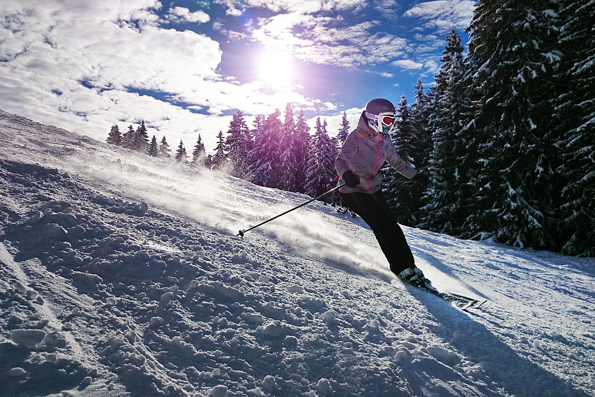 Young girl skiing downhill on snowy mountain slope