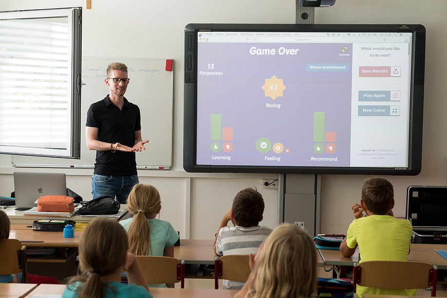 Teacher presenting interactive feedback dashboard to elementary students in classroom