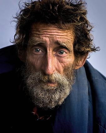 Close-up portrait of elderly homeless man with intense gaze