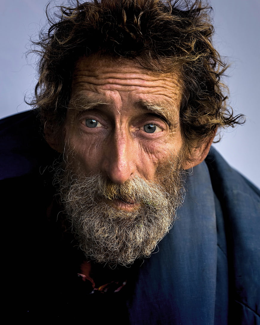 Close-up portrait of elderly homeless man with intense gaze