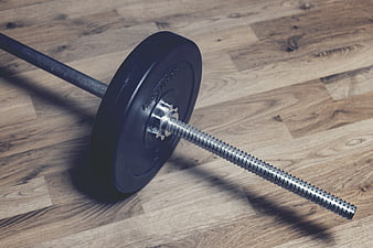 Barbell with weight plate on wooden gym floor